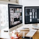 A sleek modern office setup featuring dual monitors, Apple devices, and creative decor in an indoor workspace.