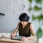 An Asian woman concentrating on digital art creation in a modern indoor workspace.